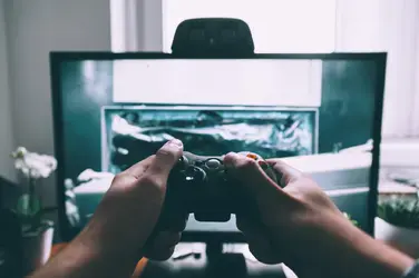 person holding game controller in front of television